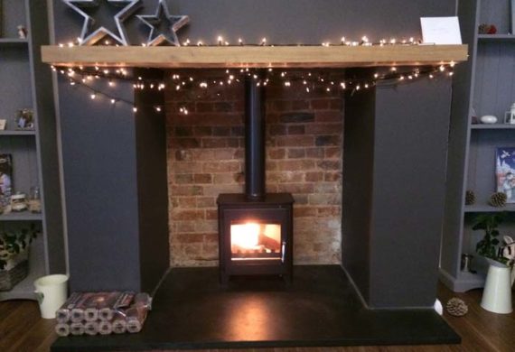 wood burning stove installed into a home with fairy lights around the fire place